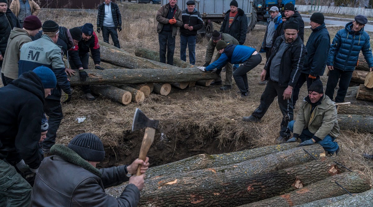 Ukrainians chop wood as they build a bunker in preparation to fight Russian troops in Hushchyntsi, Ukraine, Feb. 27, 2022. (New York Times)