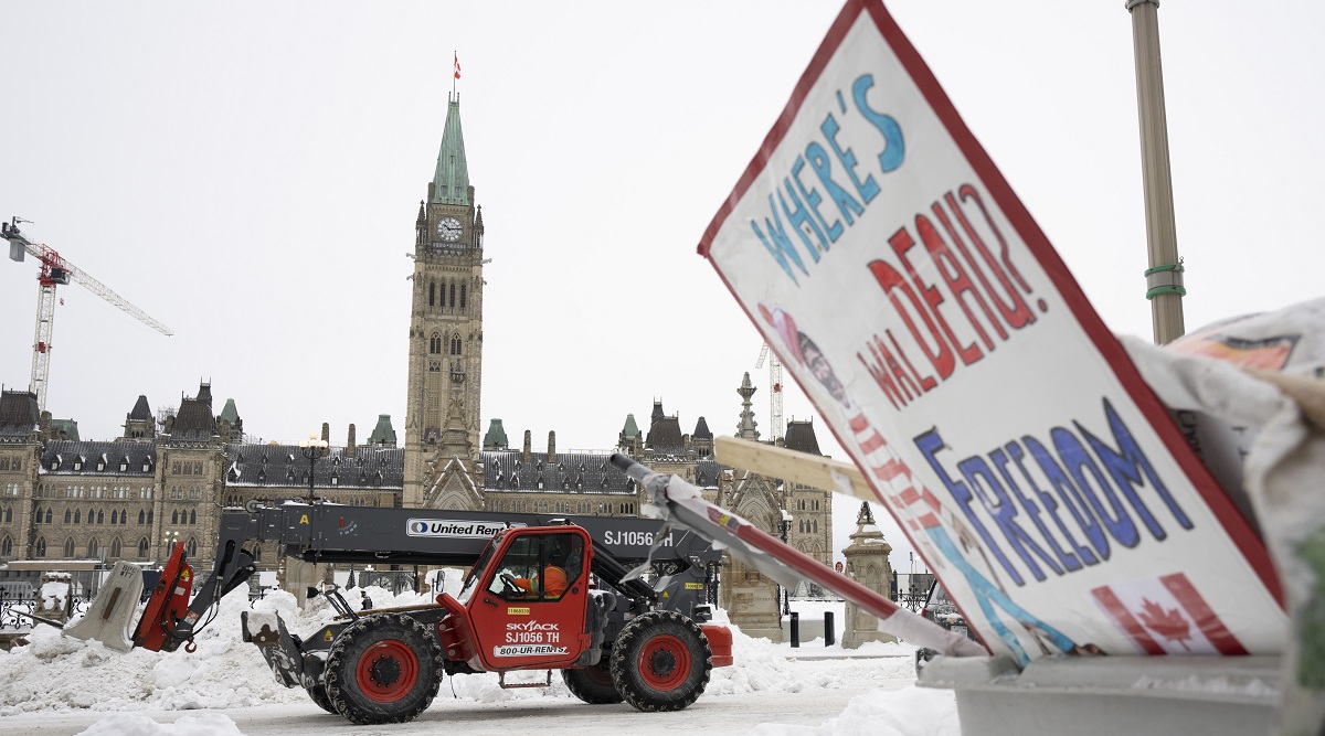 Machinery moves a concrete barricade past the Parliament buildings and a container of garbage from the trucker protest which has occupied the streets of Ottawa. (AP)