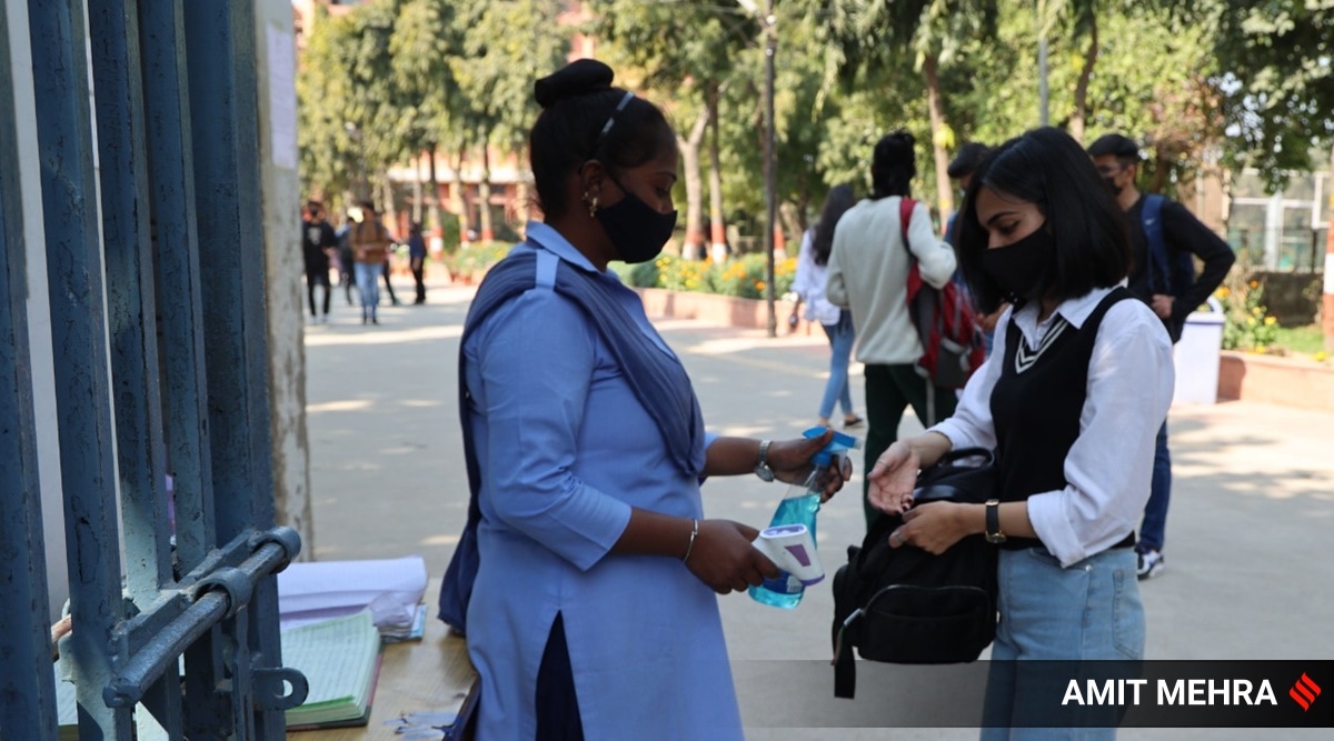 A security officer sanitised the hands of a Delhi University student. (Express Photo by Amit Mehra)