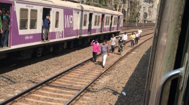 Amid power outages in Mumbai, local trains between Churchgate and Andheri came to a halt, forcing commuters to deboard trains and walk on tracks. (Express photo)