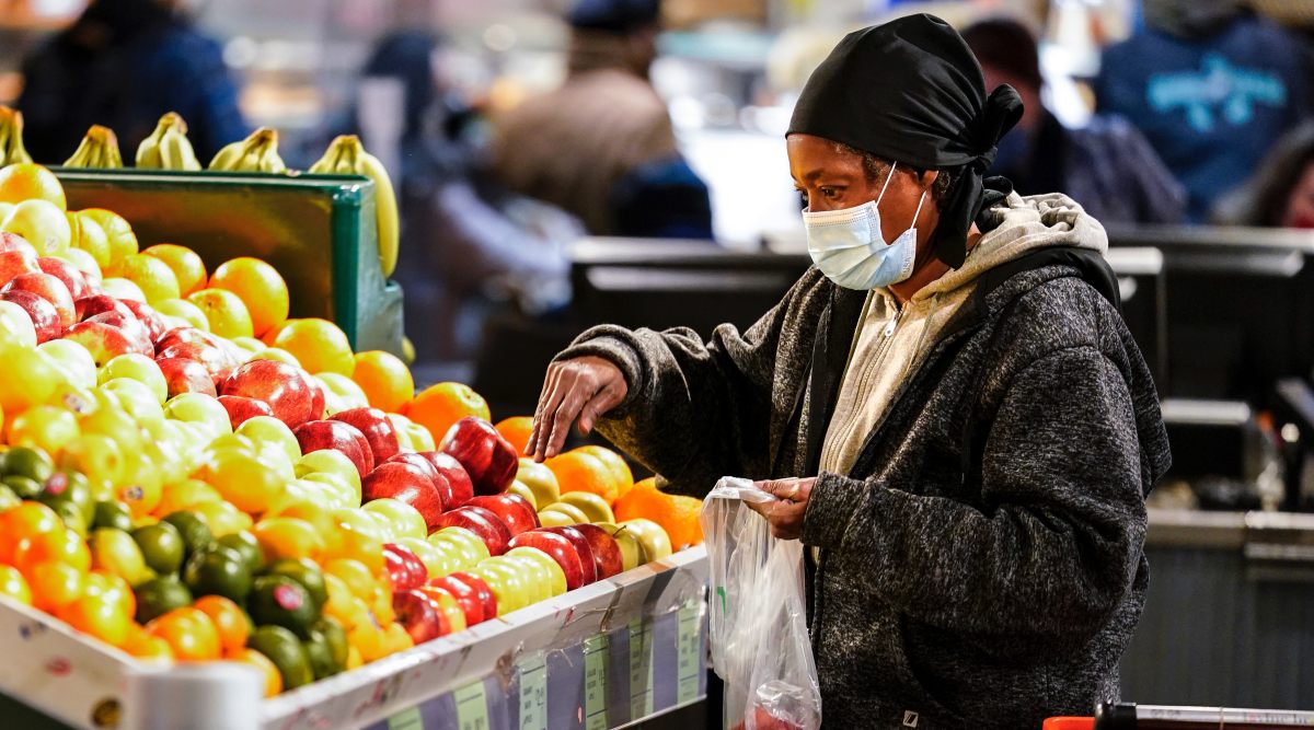 A shopper wearing a protective mask as a precaution against the spread of the coronavirus selects fruit at the Reading Terminal Market in Philadelphia, Wednesday, Feb. 16, 2022. (AP Photo/Matt Rourke)


