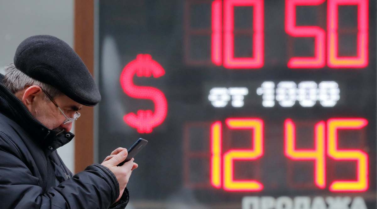 A man uses his smartphone near a board showing currency exchange rates of U.S. dollar against the Russian rouble in Saint Petersburg, Russia February 28, 2022. (REUTERS Photo)