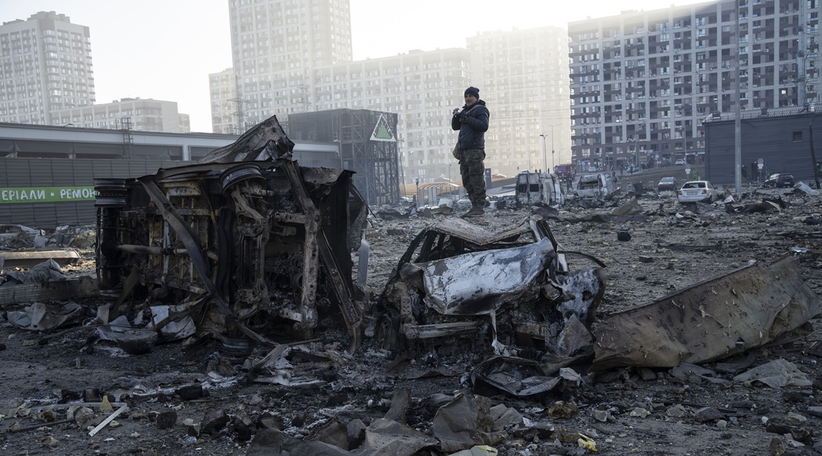 A man stands on top of a destroyed car amid the destruction caused after shelling of a shopping center, in Kyiv, Ukraine, Monday, March 21, 2022. (AP)