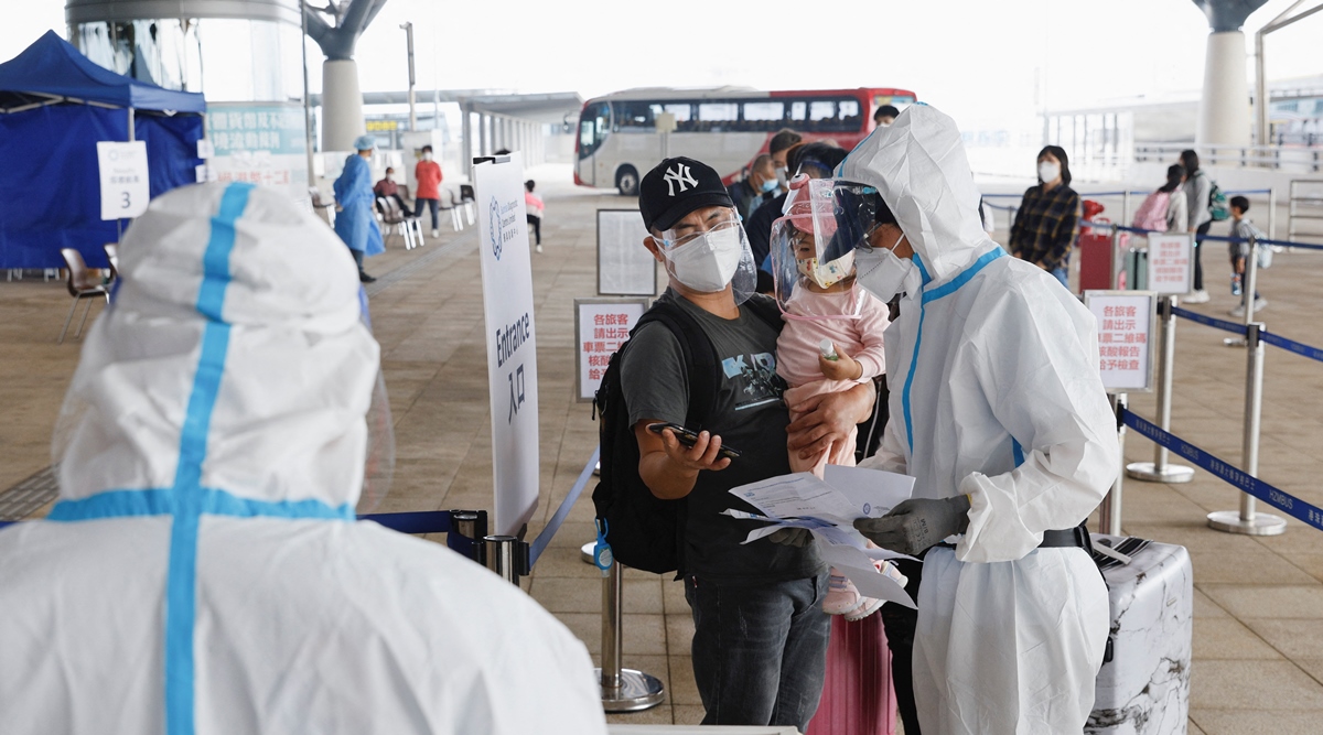A health worker wearing personal protective equipment assists people at the Hong Kong-Zhuhai-Macao Bridge Hong Kong Port, amid the coronavirus disease pandemic in Hong Kong, China, March 22, 2022. (Reuters)