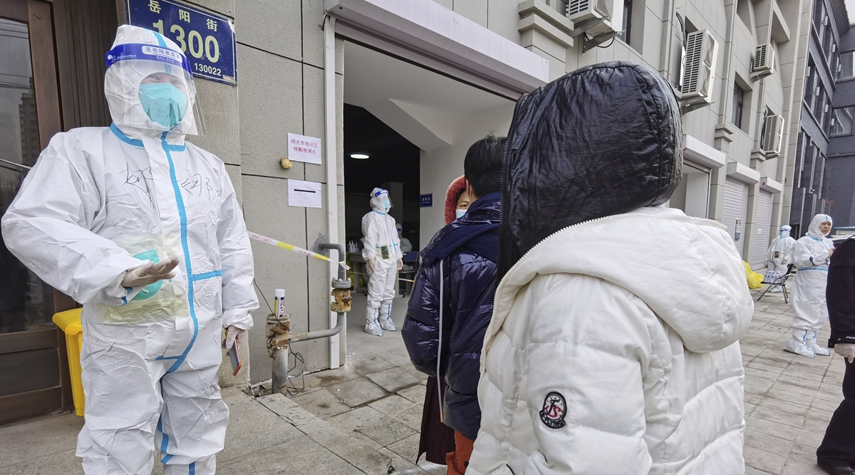 A worker wearing a protective suit speaks to residents in a neighborhood in Changchun in northeastern China's Jilin Province, March 11, 2022.(AP)