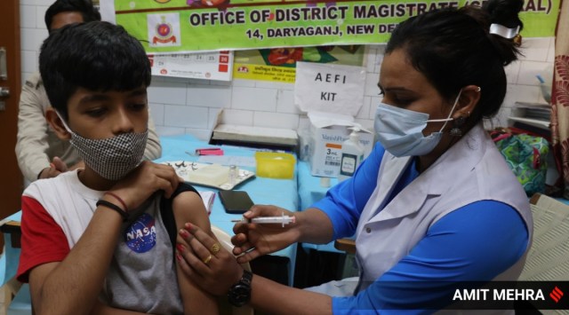 A healthcare worker administers a dose of Covid-19 vaccine to a student between the age group of 12 to 14 years at a vaccination centre in New Delhi. (Express Photo)