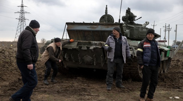 Residents of the southern Ukrainian city of Mykolaiv work to repair a captured Russian tank. (Tyler Hicks/The New York Times)
