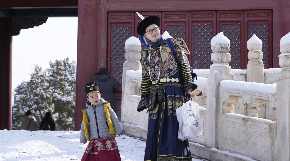 A man and child dressed in period costumes looks on at the Forbidden City on March 19, 2022 in Beijing. (AP)