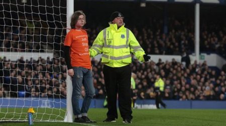 A steward stands next to a protester who tied himself to a goalpost during the match (Source: Reuters)