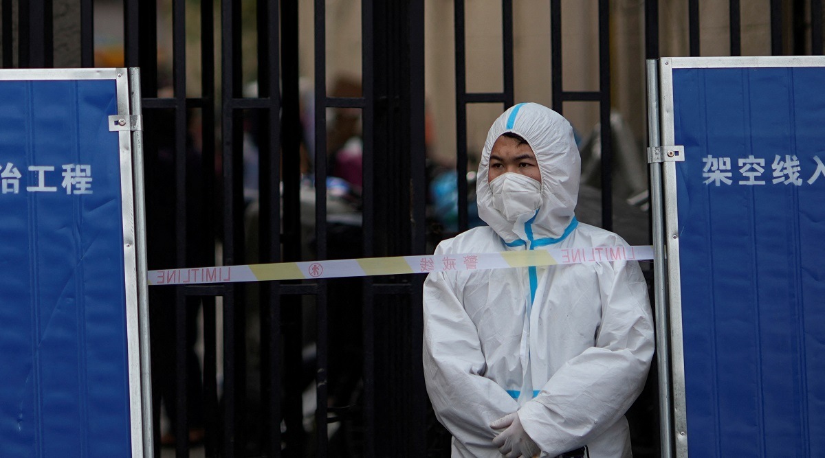 A staff worker in personal protective equipment (PPE) stands inside a barrier of an area under lockdown amid the coronavirus disease (COVID-19) pandemic, in Shanghai. (Reuters)