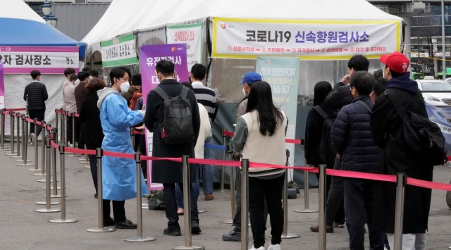 A medical worker guides people waiting for a coronavirus test at a makeshift testing site in Seoul, South Korea, Thursday, March 17, 2022.  (AP)