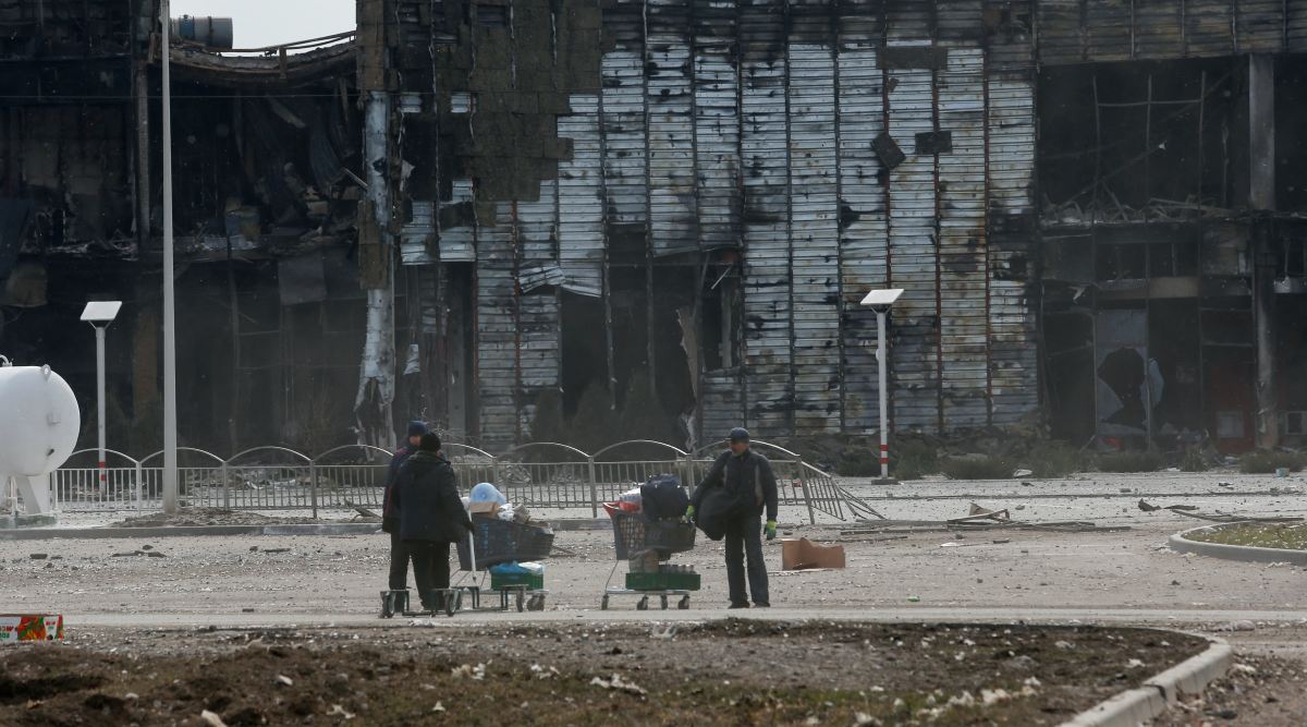 People use carts to transport belongings near a building, which was destroyed during Ukraine-Russia conflict in the besieged southern port city of Mariupol, Ukraine. (Reuters Photo)