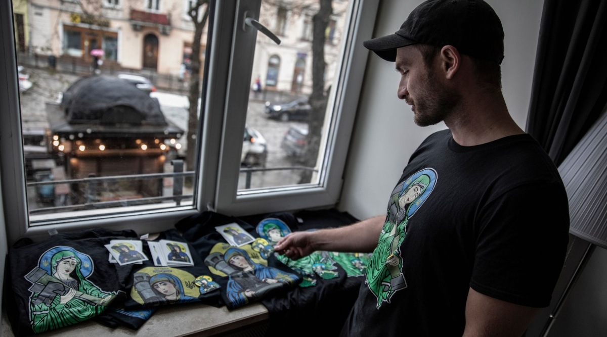 The Canadian entrepreneur Christian Borys with some of the T-shirts and stickers sold by his Toronto-based online business, which has raised $1.5 million for the Ukrainian charity Help Us Help, at his hotel room in Lviv, Ukraine, Friday. (Finbarr O’Reilly / The New York Times)
