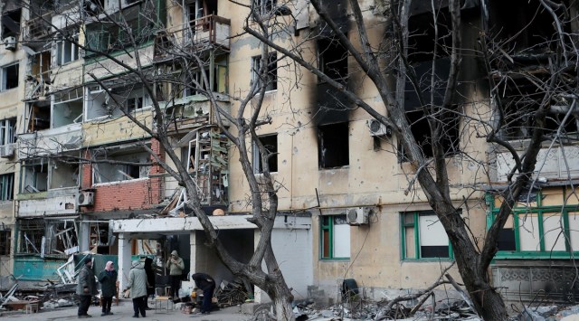 Local residents gather outside an apartment building damaged during Ukraine-Russia conflict in the southern port city of Mariupol, Ukraine. (Reuters)