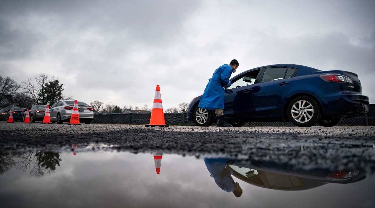 A worker checks in people arriving at a drive-through COVID-19 testing site in Baltimore, Dec. 30, 2021. (Al Drago/The New York Times)