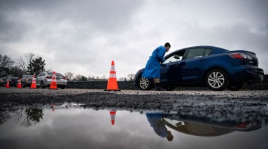 A worker checks in people arriving at a drive-through COVID-19 testing site in Baltimore, Dec. 30, 2021. (Al Drago/The New York Times)