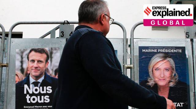 A man walks past presidential campaign posters of Emmanuel Macron Marine Le Pen in Anglet, southwestern France, Wednesday, April 8, 2022. (AP Photo/Bob Edme)

