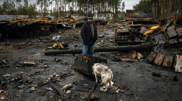 A man and his dog look at the destroyed Russian tanks and other debris on a forest road near Dmytrivka, Ukraine, on April 2, 2022. 
(Ivor Prickett/The New York Times)