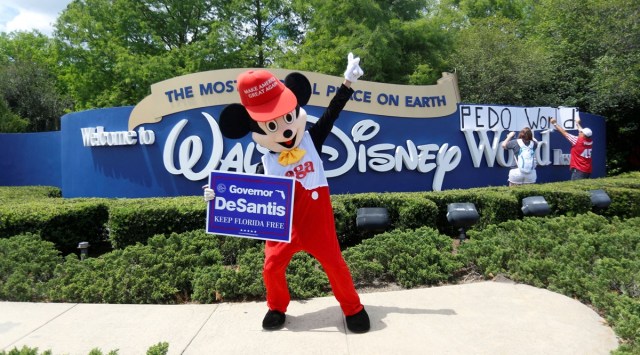 A person wearing a mouse costume dances while holding a Governor Ron DeSantis poster where supporters of Florida's Republican-backed "Don't Say Gay" bill outside Walt Disney World in Orlando, Florida, US April 16, 2022. (Reuters)