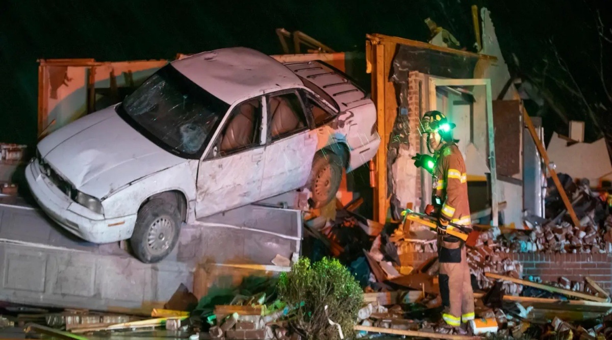 A car is seen in a pile of of debris from a home as a firefighter looks on in Andover, Kansas on April 29, 2022. (AP)