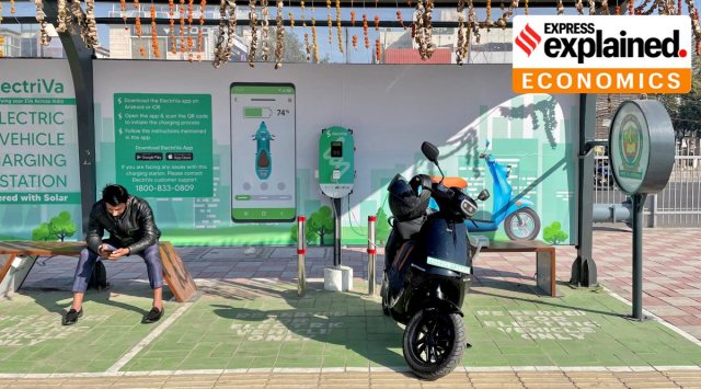 A man checks his mobile phone as he waits while recharging his Ola electric scooter at an electric vehicle charging station in New Delhi. (Reuters Photo: Aditi Shah, File)