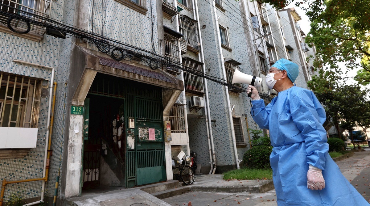 A volunteer uses a megaphone to talk to residents at an apartment building in Shanghai, China, Tuesday, April 12, 2022. (Chen Jianli/Xinhua via AP)