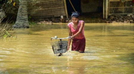 A girl pushes her bicycle as she wades through a flood-affected area in Nagaon district. (PTI Photo)