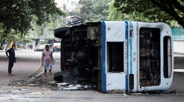 A man looks at a damaged bus of Sri Lanka's ruling party supporters after it was set on fire during a clash of pro and anti-government demonstrators near the PM's residence in Colombo. (REUTERS)