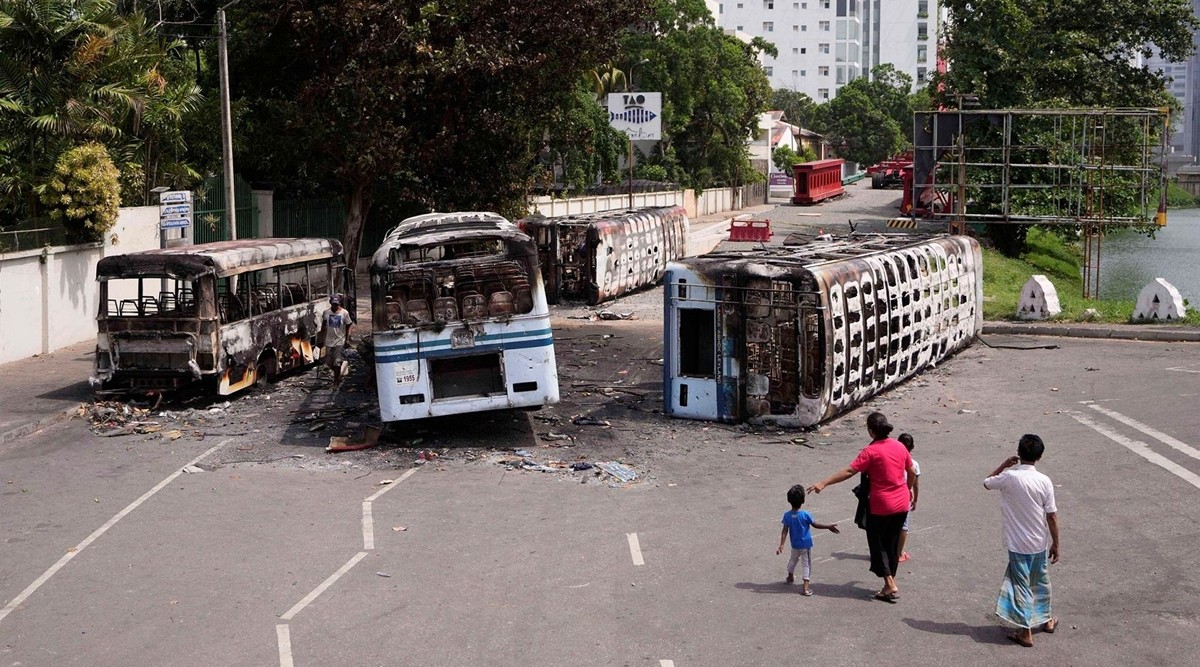 A Sri Lankan family watches the wreckage of buses burnt in clashes in Colombo. (AP/PTI)