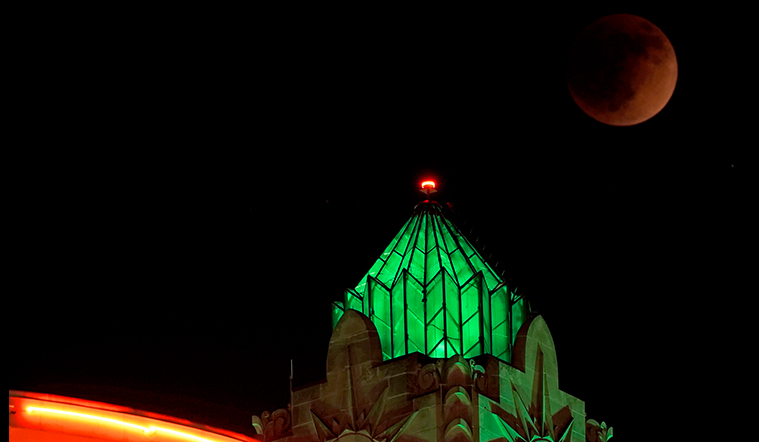 Eclipse lunar vcovering la luna a medida que se eleva más allá de los edificios en Kansas