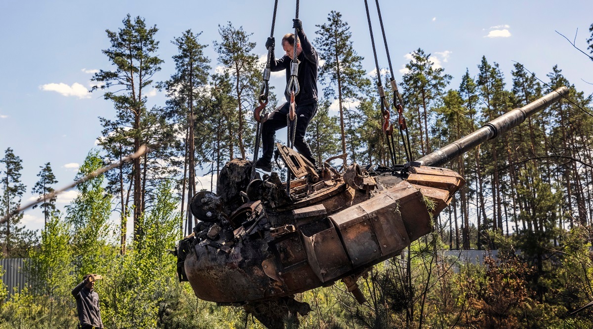 Ukrainian men use a crane while dismantling a Russian tank on the side of a road outside Kyiv, May 10, 2022. (David Guttenfelder/The New York Times)