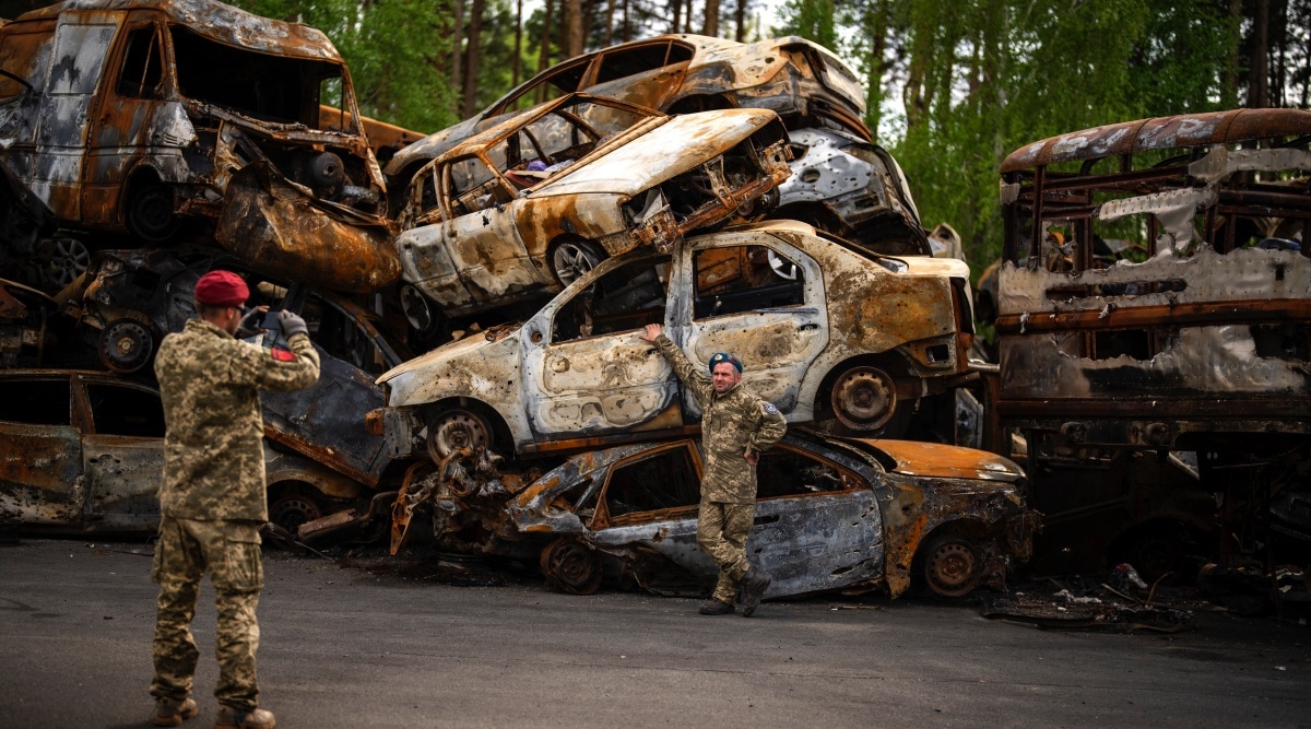 A territorial defence man poses for a photo next to cars destroyed during the Russian occupation in Irpin, on the outskirts of Kyiv. (AP)