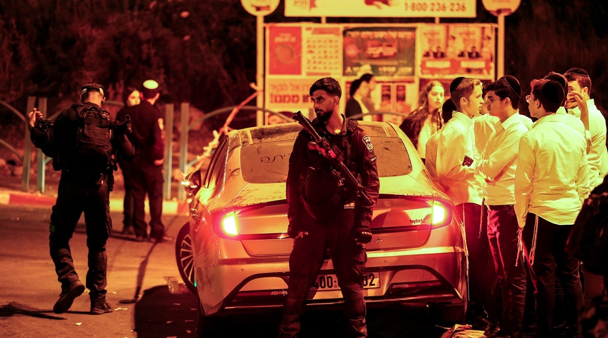 Local residents stand next to Israeli security personnel in the area where at least three people were killed in what police suspect was a Palestinian attack, on Israeli Independence Day, in Elad, Israel, May 6, 2022. (Reuters)