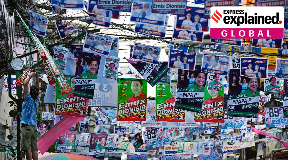 A man hangs campaign posters near a polling center in Manila, Philippines on Friday, May 6, 2022. (AP Photo/Aaron Favila)