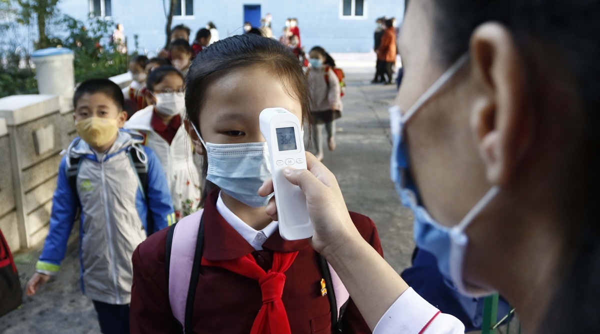 A teacher takes the body temperature of a schoolgirl to help curb the spread of the coronavirus before entering Kim Song Ju Primary School in Central District in Pyongyang, North Korea. (File/AP)