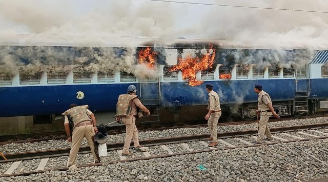 Policemen try to douse a fire in a train, set by people protesting against Centre's 'Agnipath' scheme, in Ballia. (PTI/File)
