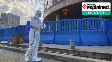 A worker in protectively overalls and carrying disinfecting equipment walks outside the Wuhan Central Hospital, China on Feb. 6, 2021. (AP Photo/Ng Han Guan, File)
