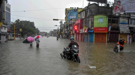 Commuters wade through a waterlogged street after heavy rains in Agartala. (PTI)