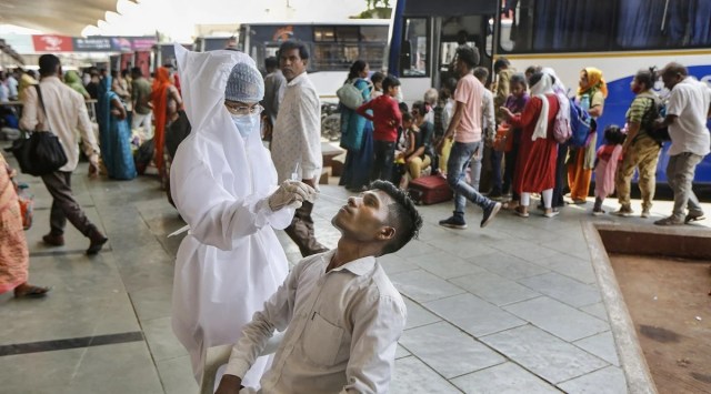 A health worker collects a swab sample of a man for Covid-19 test, at state transport bus stand, in Ahmedabad. (PTI, file)