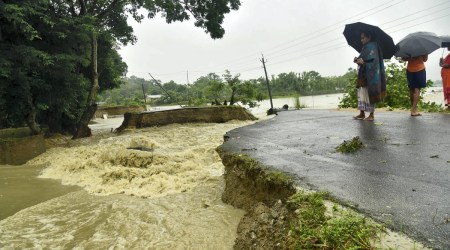 Locals look at a section of road washed away by flood waters at Dhamdhama in Nalbari district of Assam, June 17, 2022. (PTI)