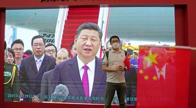 A visitor poses for a photograph in front of a TV showing Chinese president Xi Jinping at an exhibition to mark the 25th anniversary of the former British colony's return to Chinese rule, in Hong Kong. (AP)
