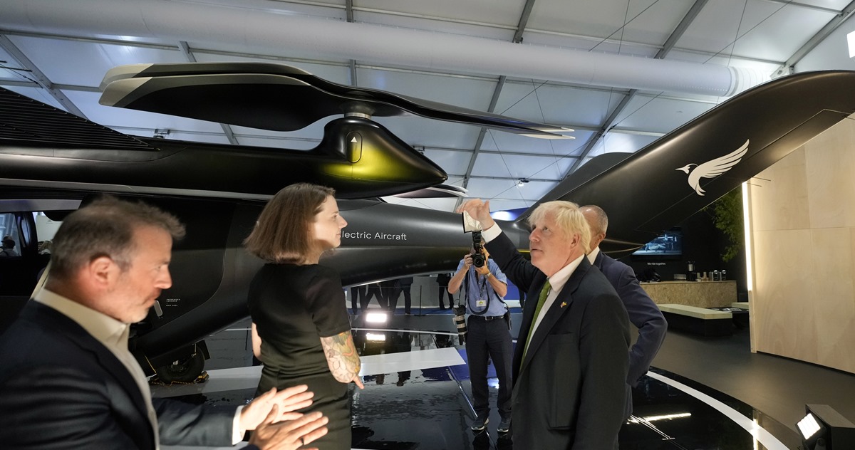 Britain's PM Boris Johnson looks at a VX4 vertical aerospace aircraft as he views the display by SaxaVord, the UK Spaceport, at the Farnborough International Airshow in Farnborough, England, Monday, July 18, 2022. (AP Photo/Frank Augstein, Pool)
