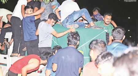 People climb on to the cage in which the leopard was trapped Sunday. (Express Photo)