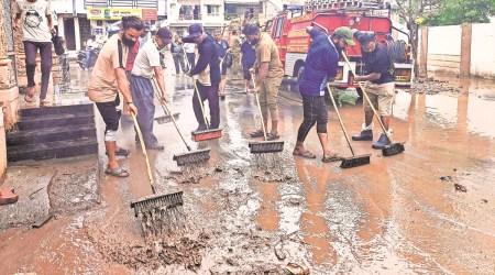 Navsari: Workers clean a road after waterlogging receded, during the monsoon season in Navsari district,(PTI Photo)