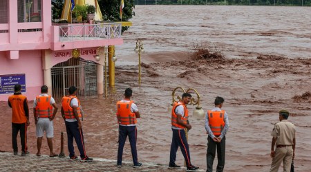 SDRF and police personnel try to assess the situation while having a look of the flooded Chenab river following incessant monsoon rains, in Akhnoor, Jammu, Thursday. (PTI)