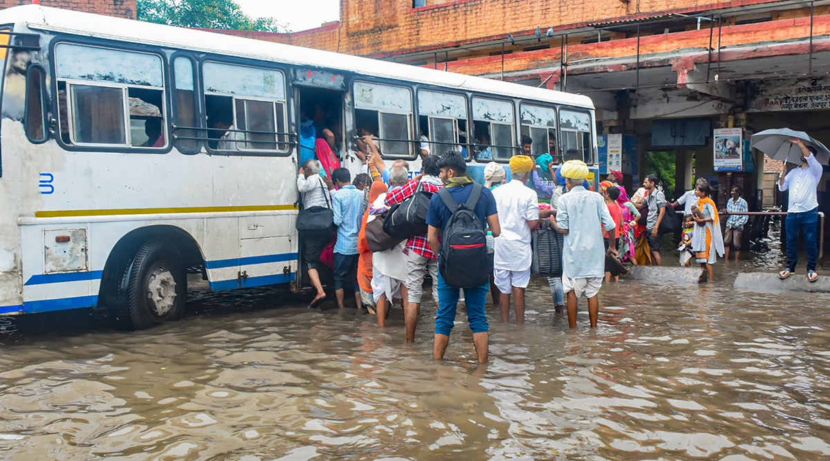 Passengers board a bus at a flooded depot after heavy rains in Jodhpur on Tuesday. (PTI)