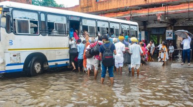 Passengers board a bus at a flooded depot after heavy rains in Jodhpur on Tuesday. (PTI)