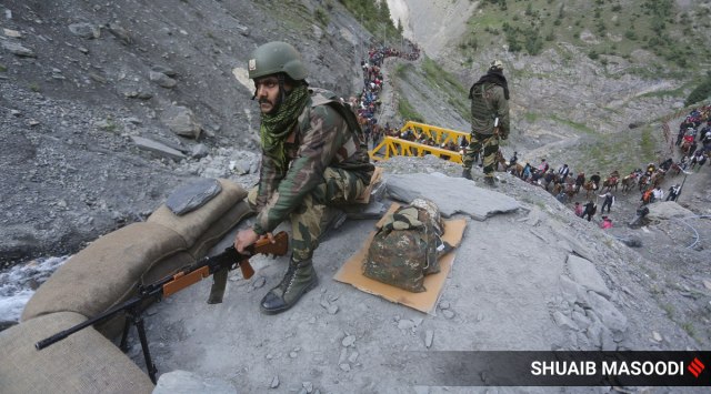 A Border Security Force (BSF) soldier stands guard as pilgrims make way to Amarnath from a base camp in Baltal. (Express Photo by Shuaib Masoodi)