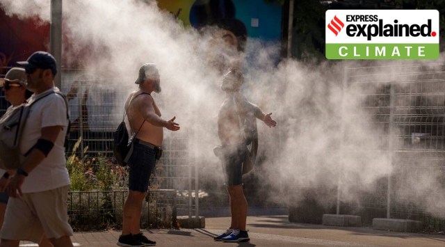 Two men cool themselves with water from a public sprinkler on a hot and sunny day in Barcelona, Spain, July 16, 2022. (AP)
