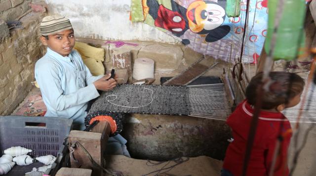 A juxtaposition represented through the mickey mouse poster in the background and the child working. (Photo: Chitvan Gill)  
